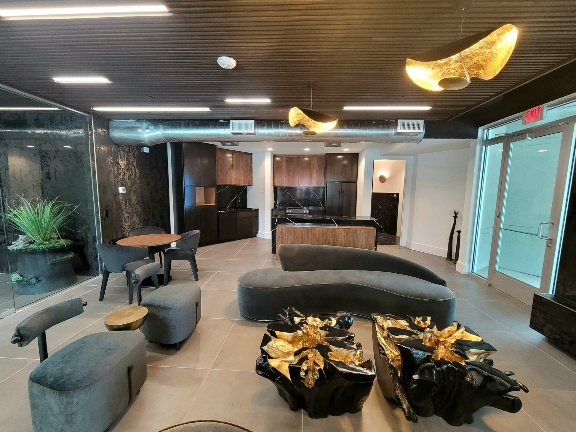 Resident lounge with curved sofa, walnut kitchen and sculptural lighting