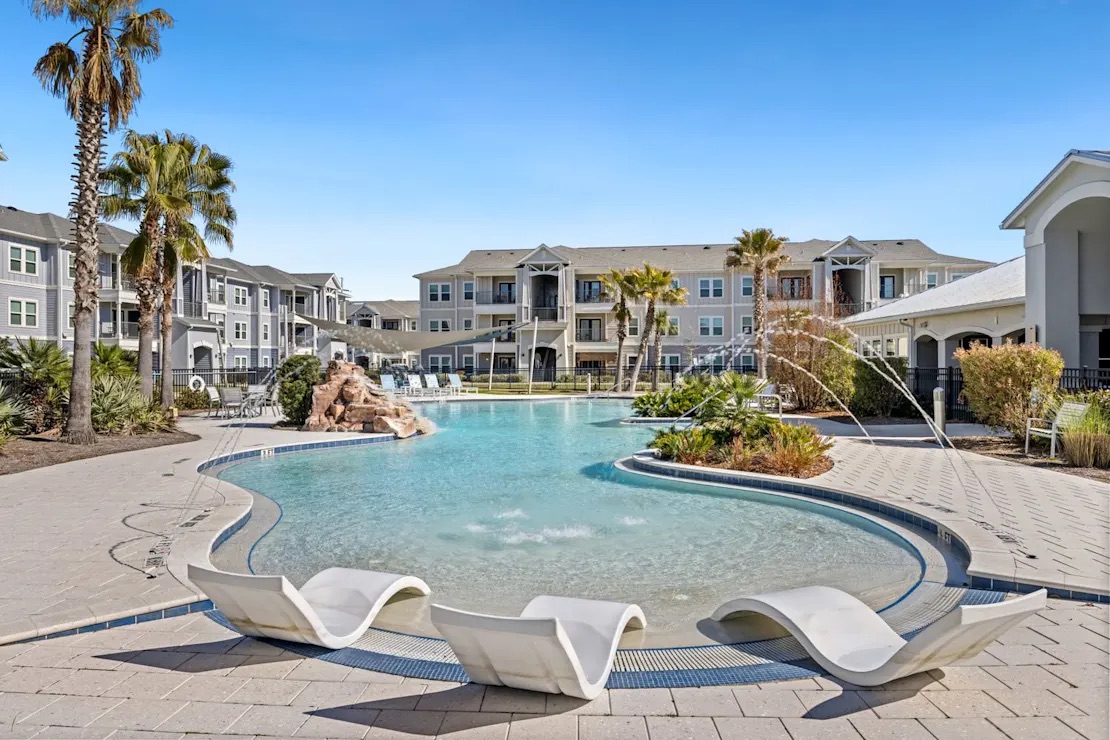 Resort-style pool with lounge chairs and palm trees